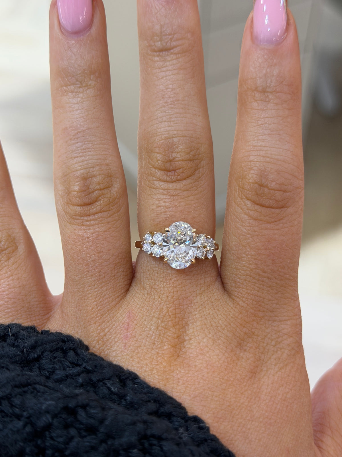 The Primrose oval lab diamond engagement ring with floral cluster shoulders, worn on the hand