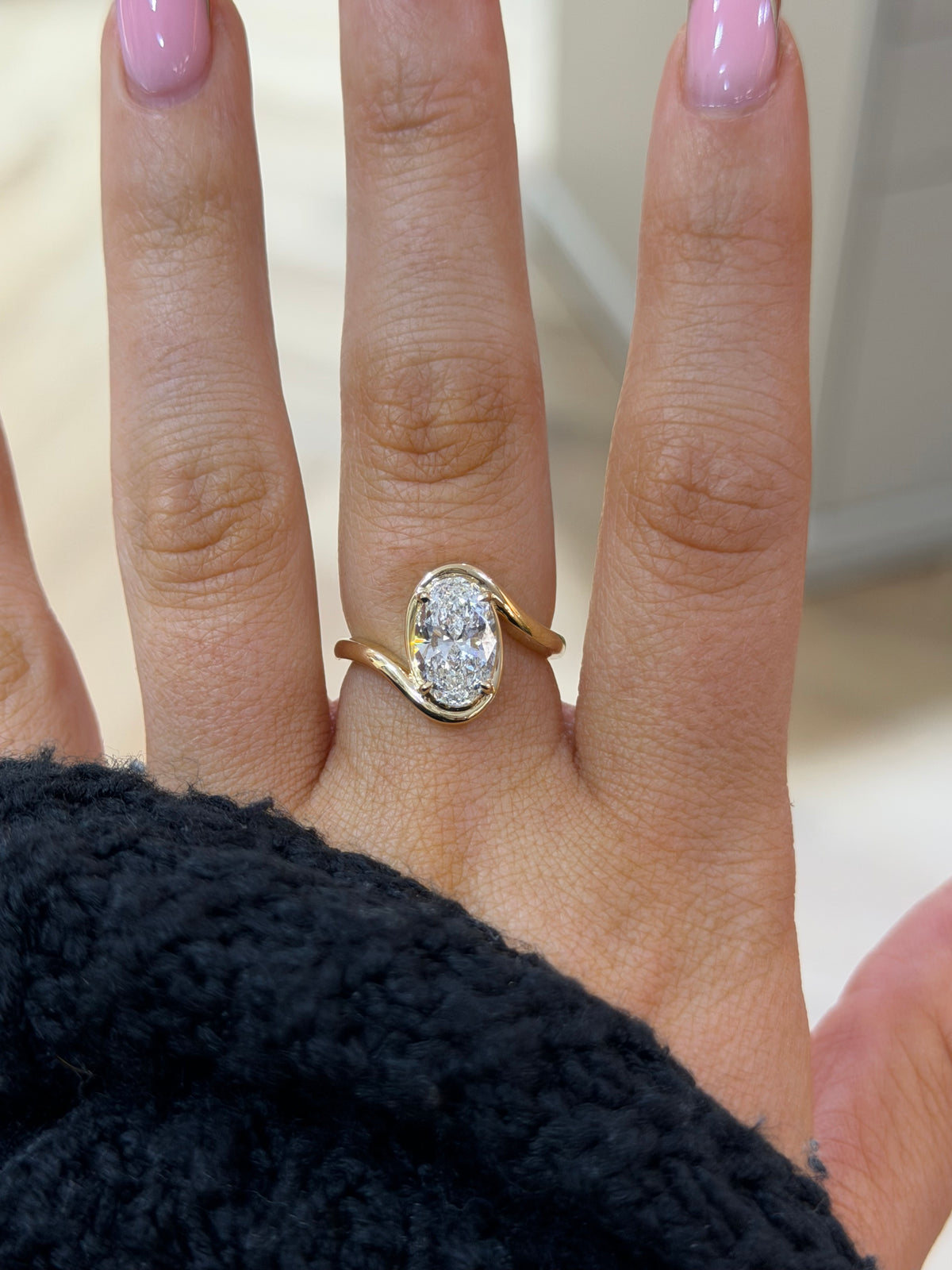 The Embrace oval lab diamond bezel engagement ring, worn on the hand