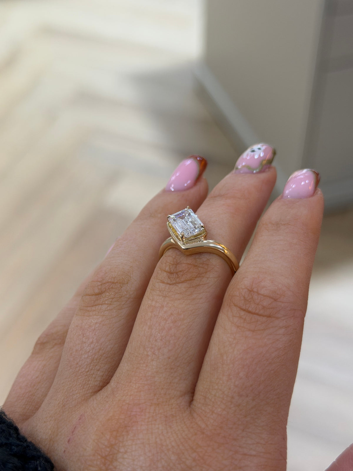 The Élan 2ct emerald cut lab diamond chevron ring in 9k yellow gold, side view on the hand