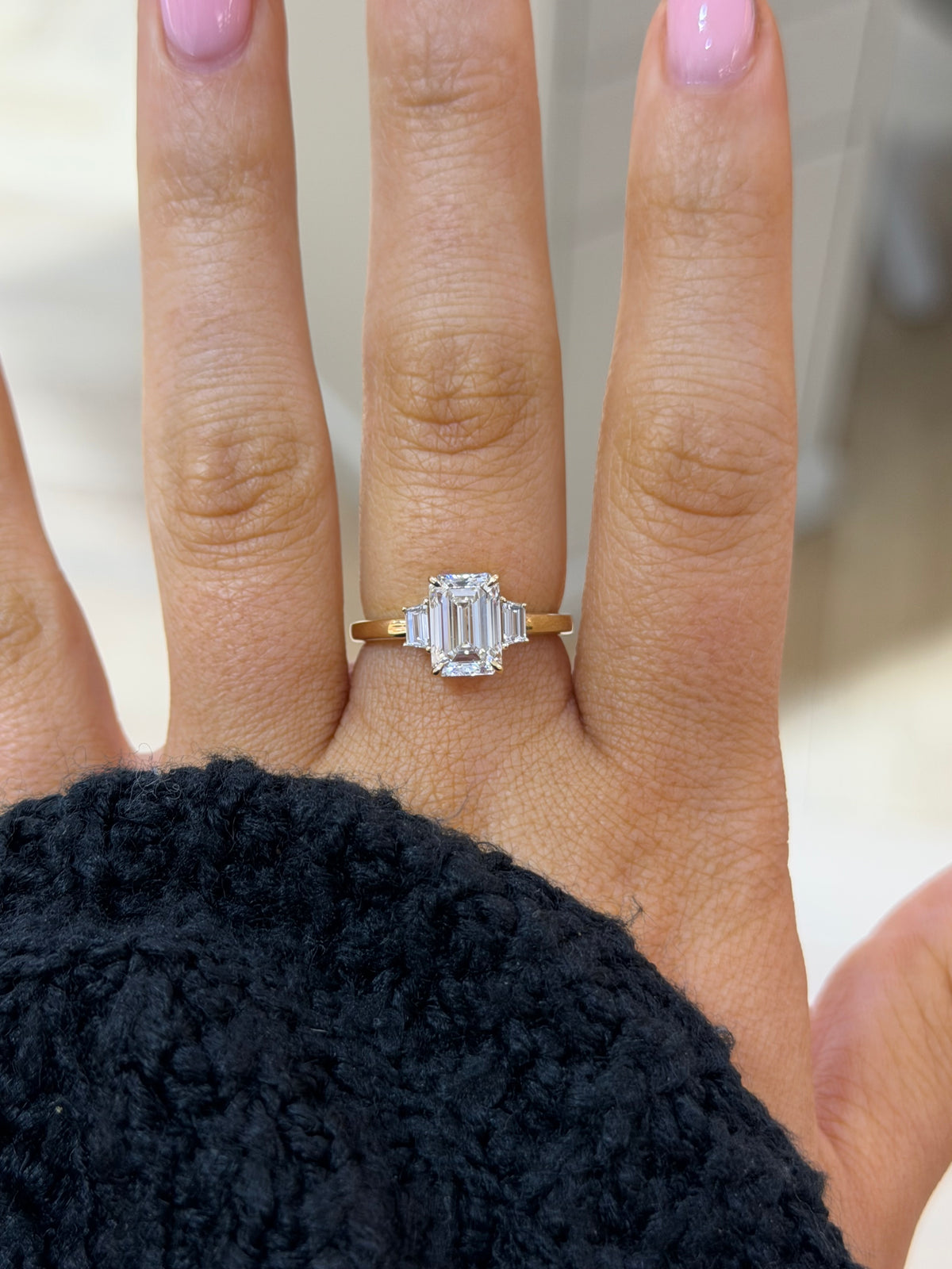 The Margot emerald cut lab diamond ring with trapezoid side stones, worn on the hand
