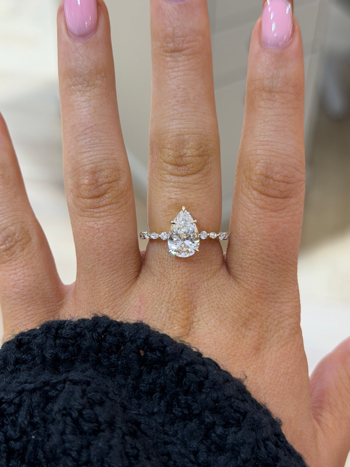 The Tear Drop pear lab diamond engagement ring with marquise and round accents, worn on the hand